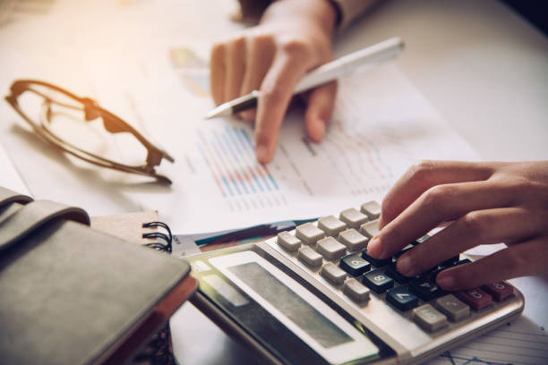 Someone working close up with calculator, glasses and pen and paper